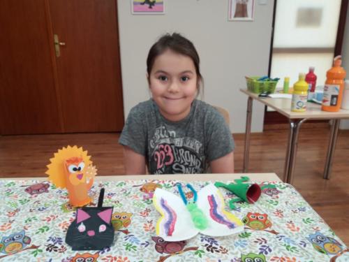 Dziewczynka z wykonanymi przez siebie zwierzętami z papieru: lwem, kotem, motylem i żabą