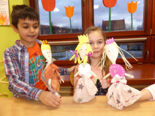 Chłopiec i dziewczynka prezentują wykonane przez siebie lalki.