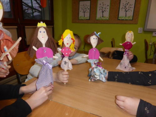 Dzieci prezentujące lalki wykonane z drewnianych łyżek, papieru oraz włóczki.
