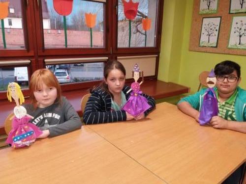 Dzieci siedzące przy stoliku z swoimi lalkami z drewnianych łyżek.