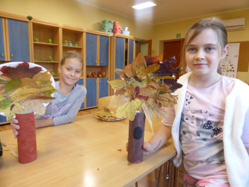 Dzieci z wykonanymi przez siebie drzewami z papieru i jesiennych liści