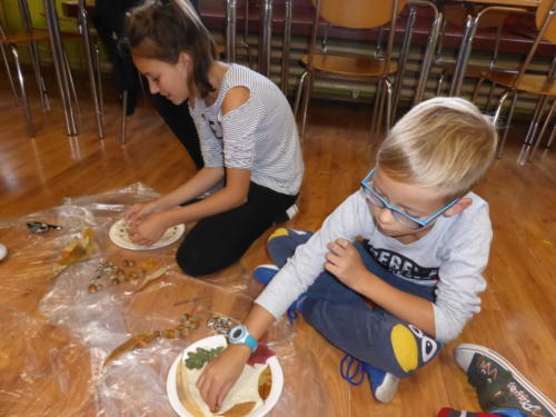 Dzieci robią obrazki z jesiennych liści, żołędzi i nasion słonecznika