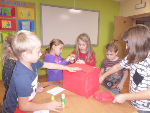 Dzieci przy stoliku, na którym jest czerwony karton.