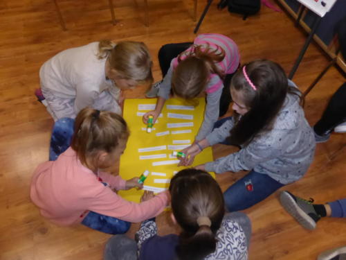 Dziewczynki przyklejające karteczki do żółtej planszy.