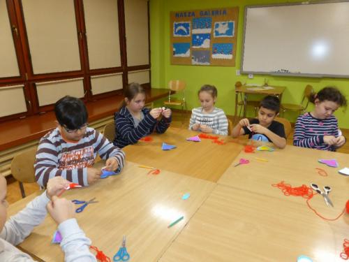 Dzieci robią prace plastyczne z papieru i włóczki